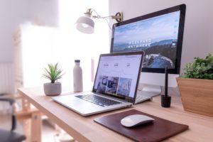 A modern desk setup with a laptop and external monitor displaying business data