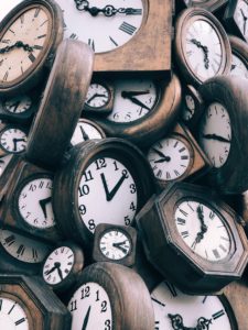 A large pile of antique clocks showing different times, representing year-end deadlines