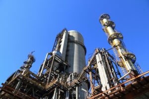 Industrial manufacturing plant with pipes and processing towers against a blue sky